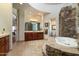 Luxurious bathroom with stone accents, a large soaking tub, and double vanities at 10630 E Cactus View Cir, Gold Canyon, AZ 85118