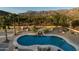 Aerial view of a kidney-shaped pool with waterfall feature and mountain backdrop at 10630 E Cactus View Cir, Gold Canyon, AZ 85118