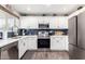 Modern kitchen with white cabinets, blue tile backsplash, and stainless steel appliances at 15725 W Post Dr, Surprise, AZ 85374