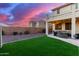 Landscaped backyard featuring a covered patio, artificial turf and a stunning sunset view at 7409 W Briles Rd, Peoria, AZ 85383