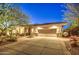 Well-lit home exterior at night, showcasing a large garage and desert landscaping at 7462 E Visao Dr, Scottsdale, AZ 85266