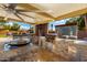 Covered outdoor kitchen with stainless steel appliances and stone counters at 9613 W Camino De Oro Dr, Peoria, AZ 85383