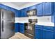 Bright kitchen with blue cabinets, black appliances, and white countertops at 1331 W Baseline Rd # 316, Mesa, AZ 85202