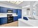 Modern kitchen with blue cabinets, black appliances, and ample counter space at 1331 W Baseline Rd # 316, Mesa, AZ 85202
