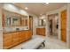 Bathroom with double vanities, a large mirror, and light wood cabinets at 25555 N Wrangler Rd, Scottsdale, AZ 85255