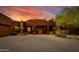 Exterior of a Southwestern style home with a brick driveway and desert landscaping at sunset at 25555 N Wrangler Rd, Scottsdale, AZ 85255
