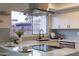 Modern kitchen with white cabinets, marble countertops, a sleek range hood, and a farmhouse sink at 8413 N 55Th Ave, Glendale, AZ 85302