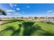 Green golf course with lake and palm trees under a partly cloudy sky at 15852 W Arrowhead Dr, Surprise, AZ 85374