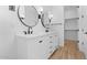 Bright bathroom features a double sink vanity, sleek fixtures, round mirrors and wood look floors at 20316 W Turney Ave, Buckeye, AZ 85396