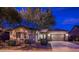 House exterior at dusk featuring a two-car garage and mature trees at 13813 W Monterey Way, Avondale, AZ 85392