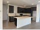 Modern kitchen featuring island, dark cabinetry, and tile backsplash at 18358 W Poston Dr, Surprise, AZ 85387