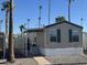 Tan mobile home with carport, steps, and storage shed; landscaped with palm trees at 2701 E Allred Ave # 110, Mesa, AZ 85204