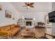 Cozy living room with leather couch, fireplace, and large TV at 6102 W Whispering Wind Dr, Glendale, AZ 85310