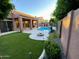 Inviting backyard oasis featuring a pool, lush landscaping, artificial grass, and a cozy fire pit at 9672 E Davenport Dr, Scottsdale, AZ 85260