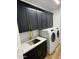 Convenient laundry area with modern black cabinets, white countertops, and full-size machines at 9672 E Davenport Dr, Scottsdale, AZ 85260