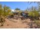 Landscaped front yard featuring natural desert plants and trees, complementing the home's southwest architecture at 10567 E Mark Ln, Scottsdale, AZ 85262