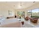 Bright main bedroom featuring a ceiling fan, sitting area, and large windows with scenic desert views at 10567 E Mark Ln, Scottsdale, AZ 85262