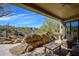 Covered outdoor patio with desert landscaping, rock fire feature, lounge seating and beautiful views at 10567 E Mark Ln, Scottsdale, AZ 85262