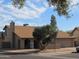 Tan two-story house with a brown roof, two-car garage, and mature landscaping at 1305 W Isabella Ave, Mesa, AZ 85202