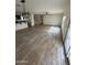 Open-concept living area with wood-look tile flooring connecting the kitchen, living room, and staircase at 16405 W Latham St, Goodyear, AZ 85338