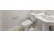 Neutral powder room featuring white toilet, pedestal sink, and light tile flooring at 17638 W Rancho Dr, Litchfield Park, AZ 85340