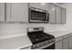 Close-up of the stainless steel microwave and gas range with gray cabinets and quartz countertops at 17644 W Rancho Dr, Litchfield Park, AZ 85340