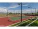 Well-lit tennis court with red and green surface, surrounded by landscaping at 18221 E Paria Canyon Dr, Rio Verde, AZ 85263