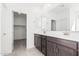 Double vanity bathroom with dark wood cabinets and walk-in closet access at 18411 W Monte Lindo Ln, Surprise, AZ 85387