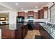 Spacious kitchen featuring dark wood cabinets, granite countertops, and stainless steel appliances at 19146 W Pasadena Ave, Litchfield Park, AZ 85340