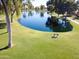 Serene lake view with lush green grass and a park bench at 25046 S Foxglenn Dr, Sun Lakes, AZ 85248