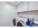 Bright laundry room features a modern washer and dryer, complemented by ample cabinet space for storage and organization at 3933 E Alfalfa Dr, Gilbert, AZ 85298