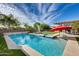 Inviting pool with sparkling water, lush landscaping, and a red umbrella at 3933 E Alfalfa Dr, Gilbert, AZ 85298