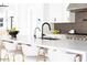 Sleek kitchen island with white countertops, black faucets, and gold barstools at 5918 E Tina Dr, Phoenix, AZ 85054