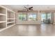 Living room with tile floors, built-in shelving, ceiling fan, and sliding glass doors at 17770 W Cottonwood Ln, Goodyear, AZ 85338