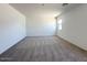 An empty bedroom with neutral carpeting and large windows that provide natural light at 47250 W Mellen Ln, Maricopa, AZ 85139