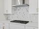 Close-up of kitchen with stainless steel hood over gas cooktop and hexagon patterned backsplash at 4816 N 177Th Ln, Goodyear, AZ 85395