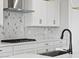 Modern kitchen featuring white cabinets, a marble backsplash, and a black faucet at 4816 N 177Th Ln, Goodyear, AZ 85395