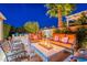 Relaxing backyard featuring a modern tile fire pit with comfortable seating and a mature palm tree at 1397 E Verde Blvd, Queen Creek, AZ 85140