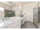 Elegant bathroom with white cabinets, dual sinks, a spacious mirror, and glass-enclosed shower area at 20496 W Valley View Dr, Buckeye, AZ 85396