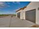 Two-car garage with dark gray doors and a view of farmland at 22859 W Euclid Ave, Buckeye, AZ 85326