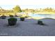 Landscaped backyard with gravel and bushes overlooks lake at 26409 S Moonshadow Dr, Sun Lakes, AZ 85248