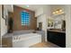 Bathroom with soaking tub, granite countertop, and block glass window at 6033 E Pebbles Ct, Cave Creek, AZ 85331