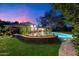 Backyard oasis featuring a pool, lush landscaping, and an inviting outdoor dining area at twilight at 8031 N 14Th Ave, Phoenix, AZ 85021