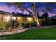 Landscaped backyard with brick pathway, mature trees, a tree swing, and outdoor lighting at dusk at 8031 N 14Th Ave, Phoenix, AZ 85021