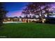 Spacious backyard with lush green lawn, mature trees, brick accents, and a view of the pool area at dusk at 8031 N 14Th Ave, Phoenix, AZ 85021