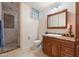 A neutral-toned bathroom featuring a glass block window, a wooden vanity and a walk-in shower at 8031 N 14Th Ave, Phoenix, AZ 85021