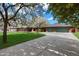 Spacious home featuring a long driveway, three-car garage and flowering trees under a bright blue sky at 8031 N 14Th Ave, Phoenix, AZ 85021