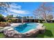 A backyard featuring a large pool, manicured green grass, and mature trees with a house in the background at 8031 N 14Th Ave, Phoenix, AZ 85021