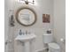 Modern powder room with pedestal sink, stylish mirror, and updated fixtures at 9236 E Canyon View Rd, Scottsdale, AZ 85255