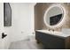 Elegant powder room with a large round mirror and modern vanity at 10944 E Whistling Wind Way, Scottsdale, AZ 85255